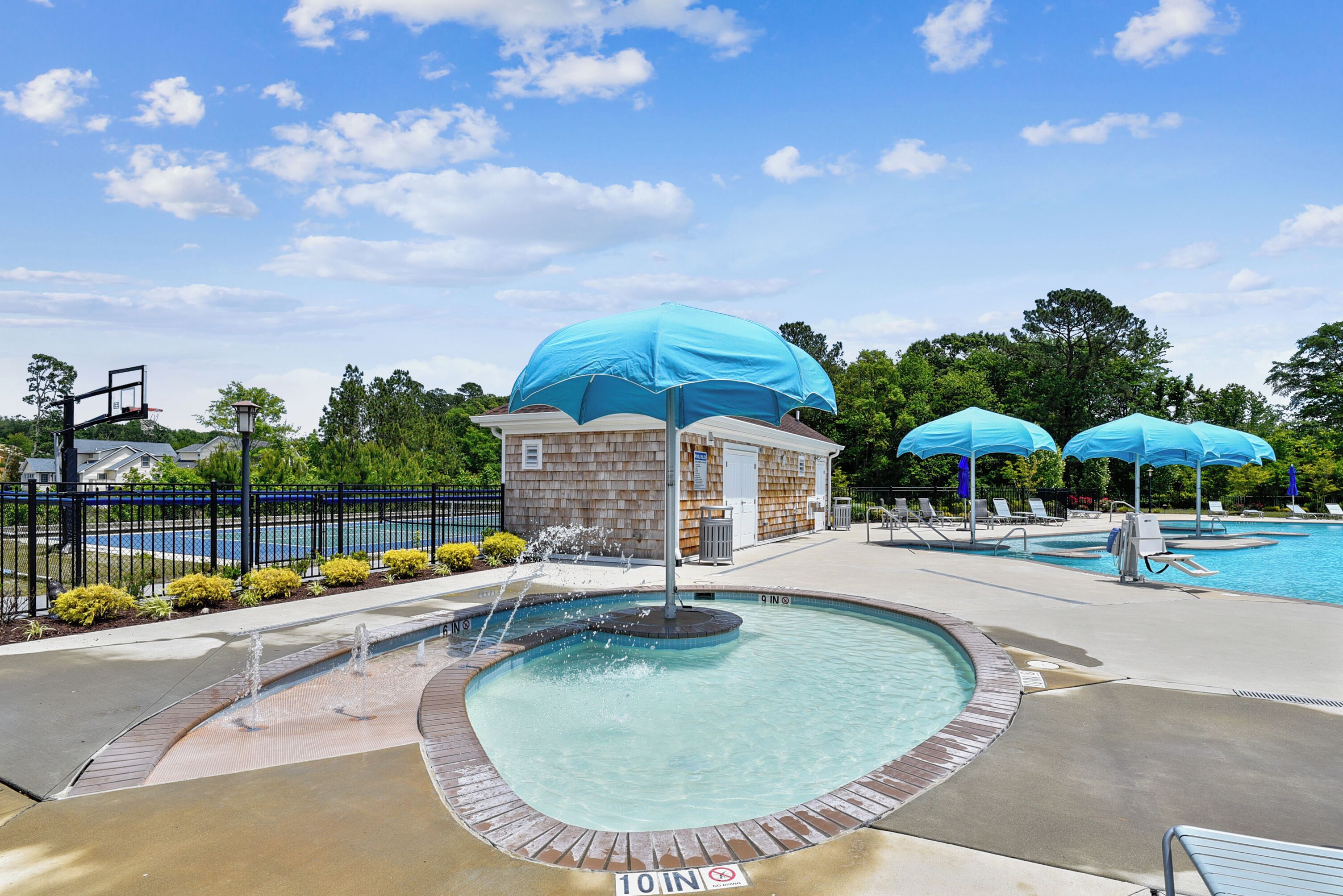 Un espace piscine agrémenté d’une fontaine, de chaises longues et de parasols.