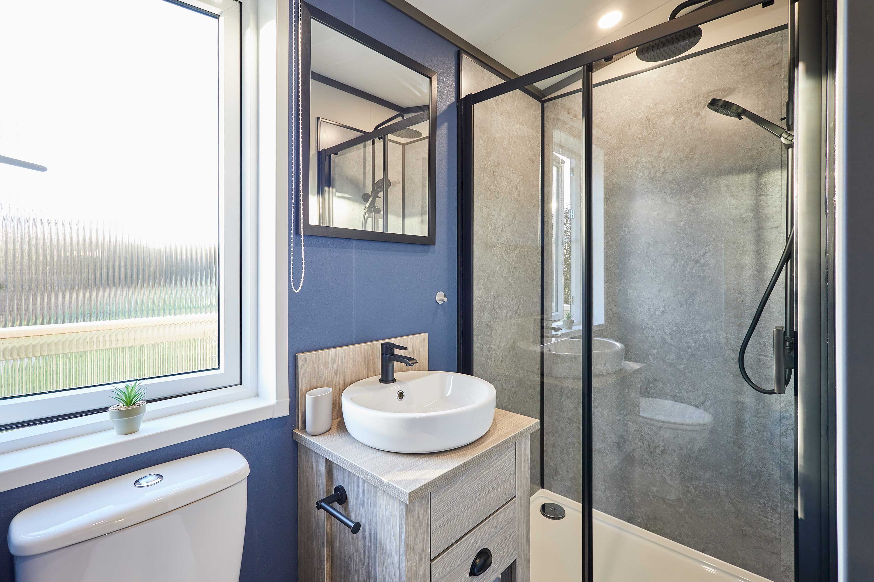 A modern bathroom with a white sink, a toilet, and a glass-enclosed shower.