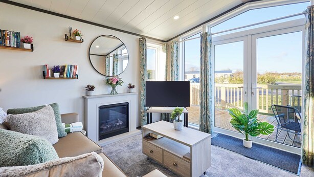 Ein Wohnzimmer mit Kamin, Flachbildfernseher, einer Couch und einem Balkon mit Blick.