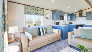 Ein modernes Wohnzimmer mit einem beigen Sofa, einem Couchtisch und Blick auf die Küche.