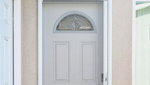A front door with a decorative glass panel, a doorbell, and a potted plant with red flowers. - Comfy Retreat With Yard Cozy Interiors (San Gabriel)