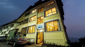 A multi-story building with a sign indicating a hotel. - Indira Nature Valley (Mahabaleshwar)