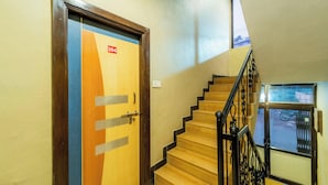 A staircase with wooden steps and black metal railings, leading to a door with a number plate. - Indira Nature Valley (Mahabaleshwar)