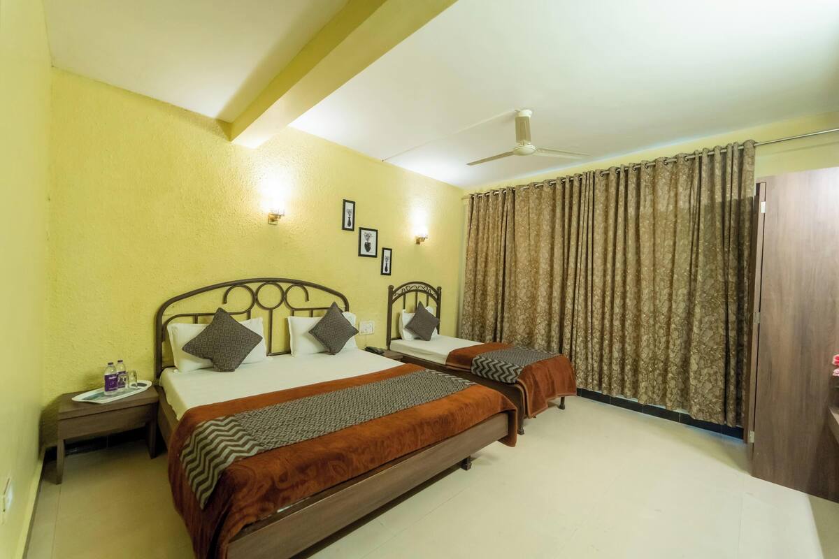 A hotel room with two beds, a ceiling fan, and a curtain.