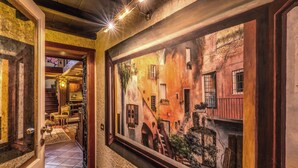 A corridor with a mural of a street scene, wooden doors, and a staircase leading to another room. - Campo de Fiori - Eleanor Suite luxury & history 1BD 1BH (Roma)