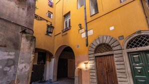 A narrow cobblestone street with yellow buildings, a wooden door, and an arched entrance. - Campo de Fiori - Eleanor Suite luxury & history 1BD 1BH (Roma)