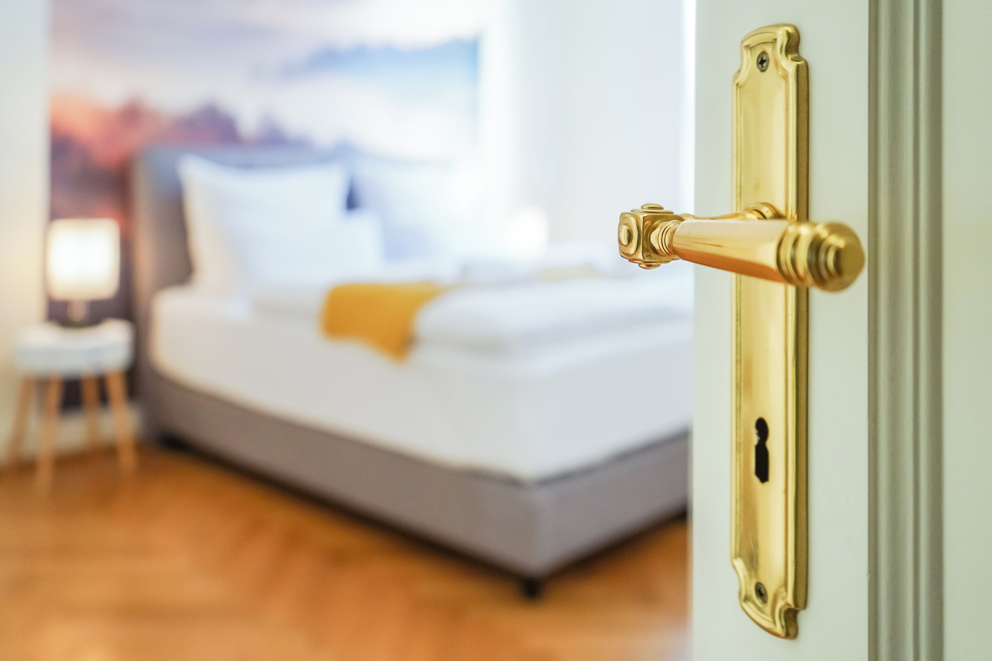 A bedroom with a bed, a nightstand, and a door with a golden handle.