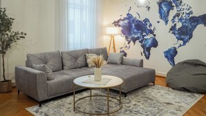 A modern living room with a grey sofa, a round coffee table, and a world map on the wall. - 7Seas Apartment Luxus-Altbau (Saarbrücken)