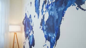 Een kamer met een groot abstract blauw kunstwerk aan de muur, een vloerlamp en een raam met gordijnen.