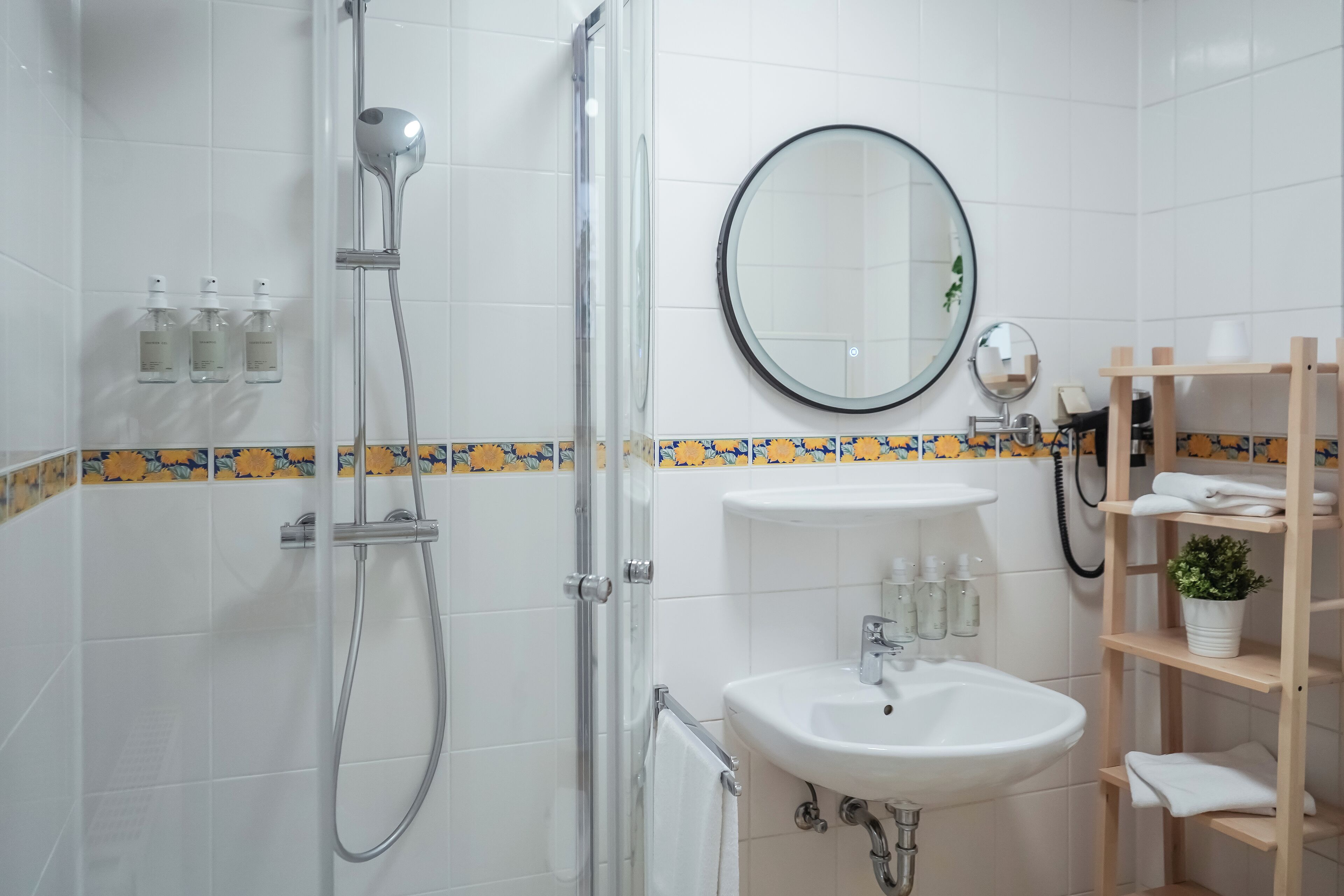 A modern bathroom with a glass-enclosed shower, a white sink, and a mirror.