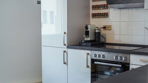 A modern kitchen with white cabinetry, a built-in oven, and a coffee maker on the countertop. - 7Seas Apartment Luxus-Altbau (Saarbrücken)