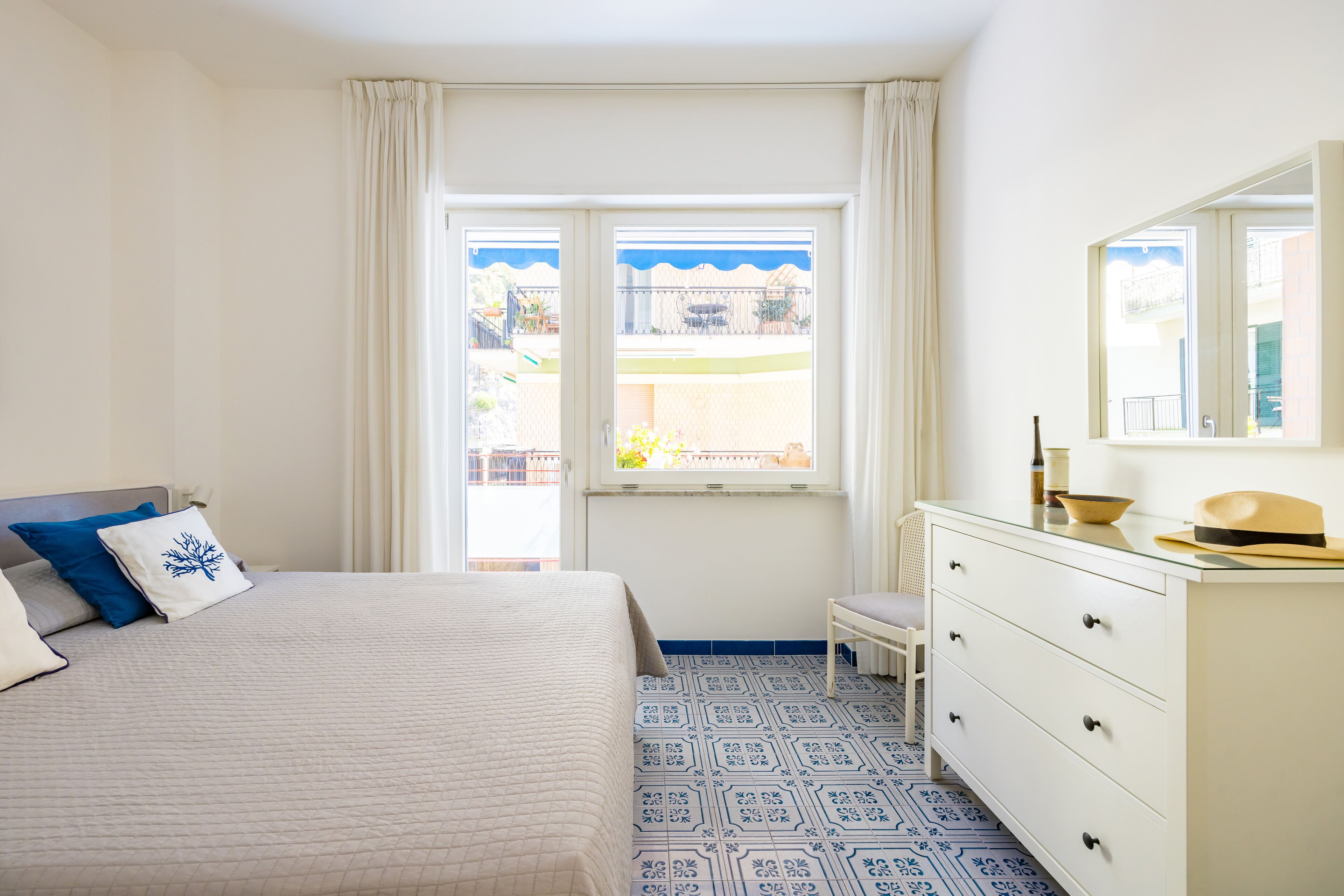 A bedroom with a bed, a dresser, a window, and a view of the outside.