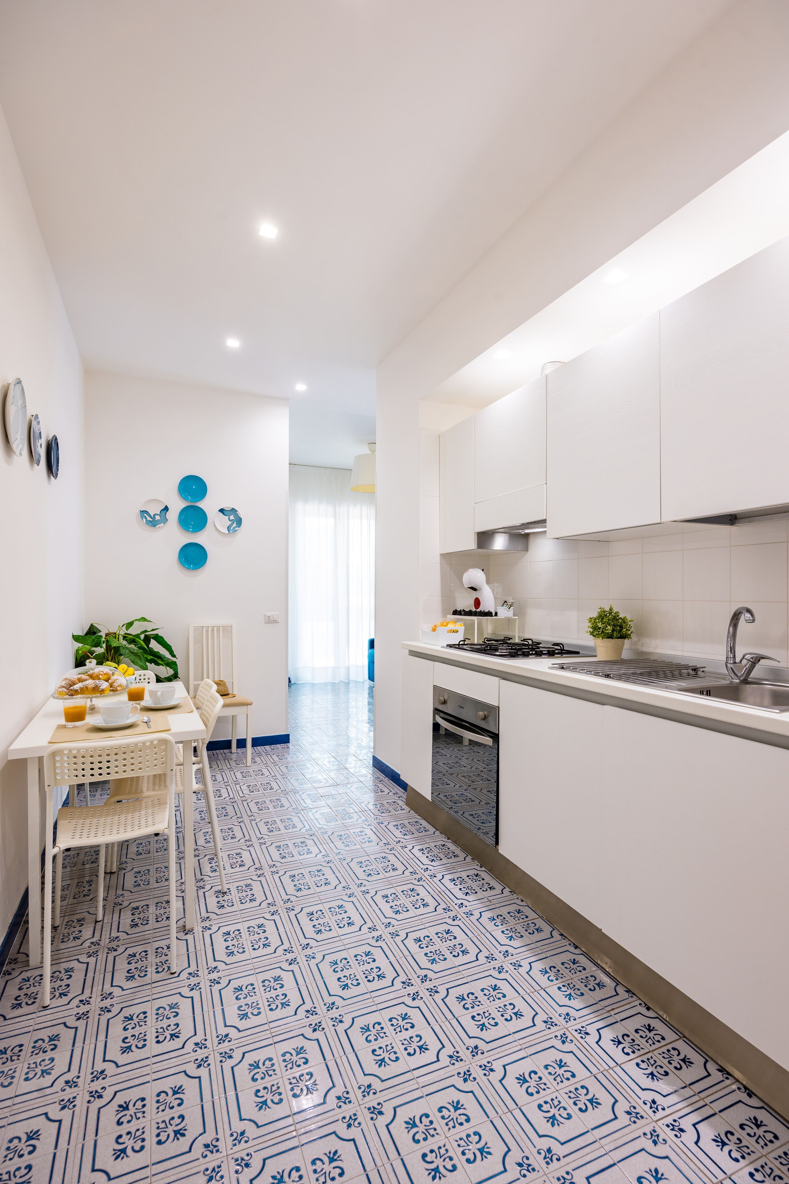 Een moderne keuken met witte kastjes, een roestvrijstalen spoelbak en een betegelde spatwand.