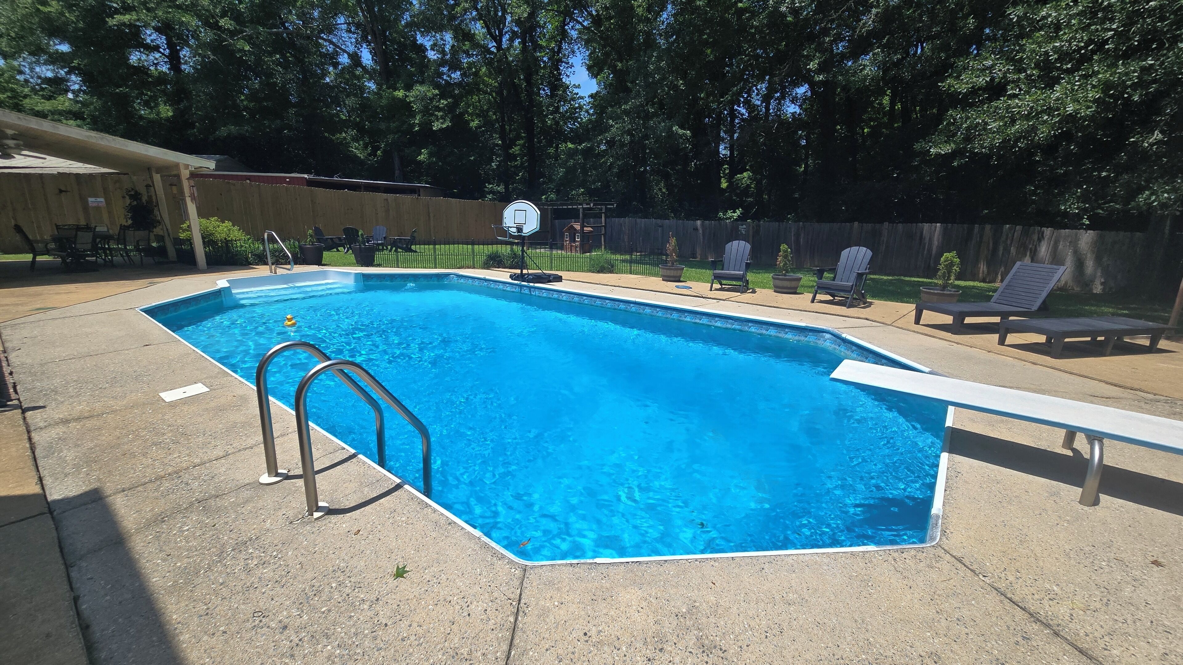 Una piscina rectangular con una escalera metálica en un lateral, rodeada por una plataforma de hormigón.