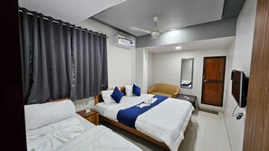 Une chambre d’hôtel avec deux lits, un ventilateur de plafond, une télévision et un miroir.