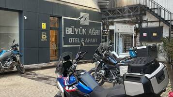Uma motocicleta estacionada em frente a um edifício com uma placa que diz 'BUYUK AGRI OTEL & APART'.