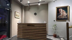 Un comptoir d’accueil avec une pancarte indiquant « RÉCEPTION », une horloge, une œuvre d’art encadrée et une plante en pot.