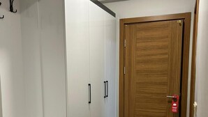 Un couloir avec une porte en bois, une armoire blanche avec des poignées noires et un plancher en bois.
