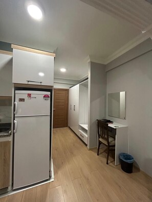 A compact kitchen with a refrigerator, a wooden cabinet, and a white countertop. - Buyuk Agri Hotel (Agri)