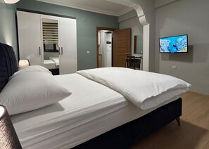 A bedroom with a bed, a TV on the wall, and a bathroom visible through an open door. - Buyuk Agri Hotel (Agri)