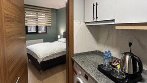 Une chambre d’hôtel compacte équipée d’un lave-linge, d’une petite kitchenette et d’un lit donnant sur une vue agréable.