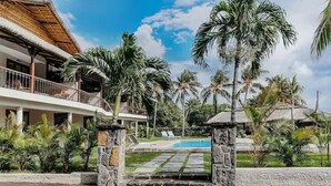 A resort with a pool, palm trees, and a thatched-roof building. - Boutik Le Morne Holiday Apartments (Le Morne)