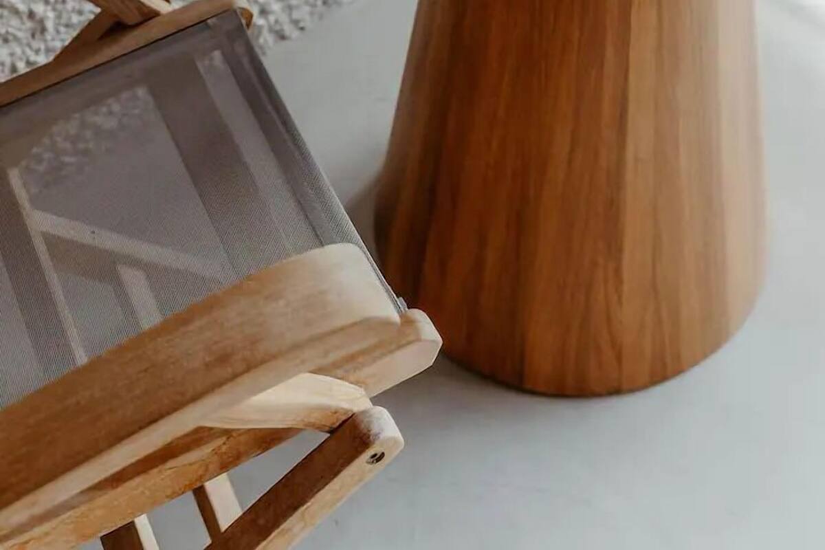 Una mesa redonda con base de madera y superficie gris, que sostiene cuatro cuencos negros y dos tazas.