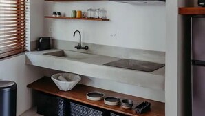 A modern kitchen with a central island, built-in shelves, a stainless steel refrigerator, and a window with blinds. - Boutik Le Morne Holiday Apartments (Le Morne)