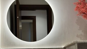 A bathroom with a round mirror, a white sink, and a towel. - Mynt stay hotel apartment - zed towers (Sheikh Zayed City)