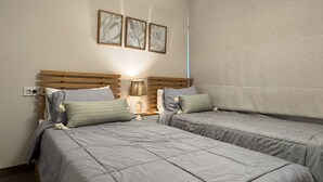 A bedroom with two beds, a nightstand with a lamp, and three framed pictures on the wall. - Mynt stay hotel apartment - zed towers (Sheikh Zayed City)
