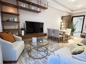 Relax in a stylish living room with a large flat-screen TV, comfortable seating area, and a dining table.