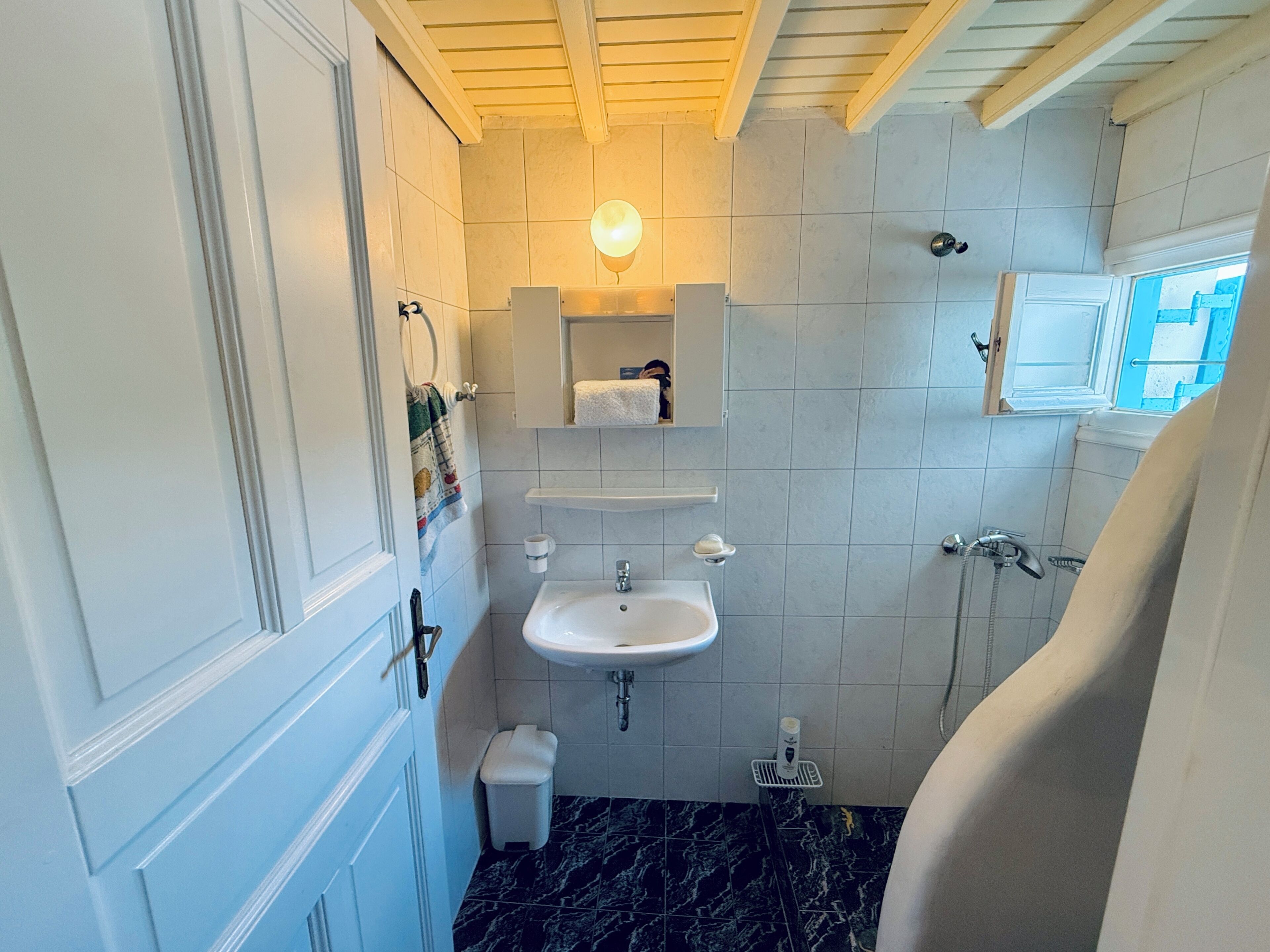 A bathroom with a white sink, a mirror, a towel rack, and a shower.