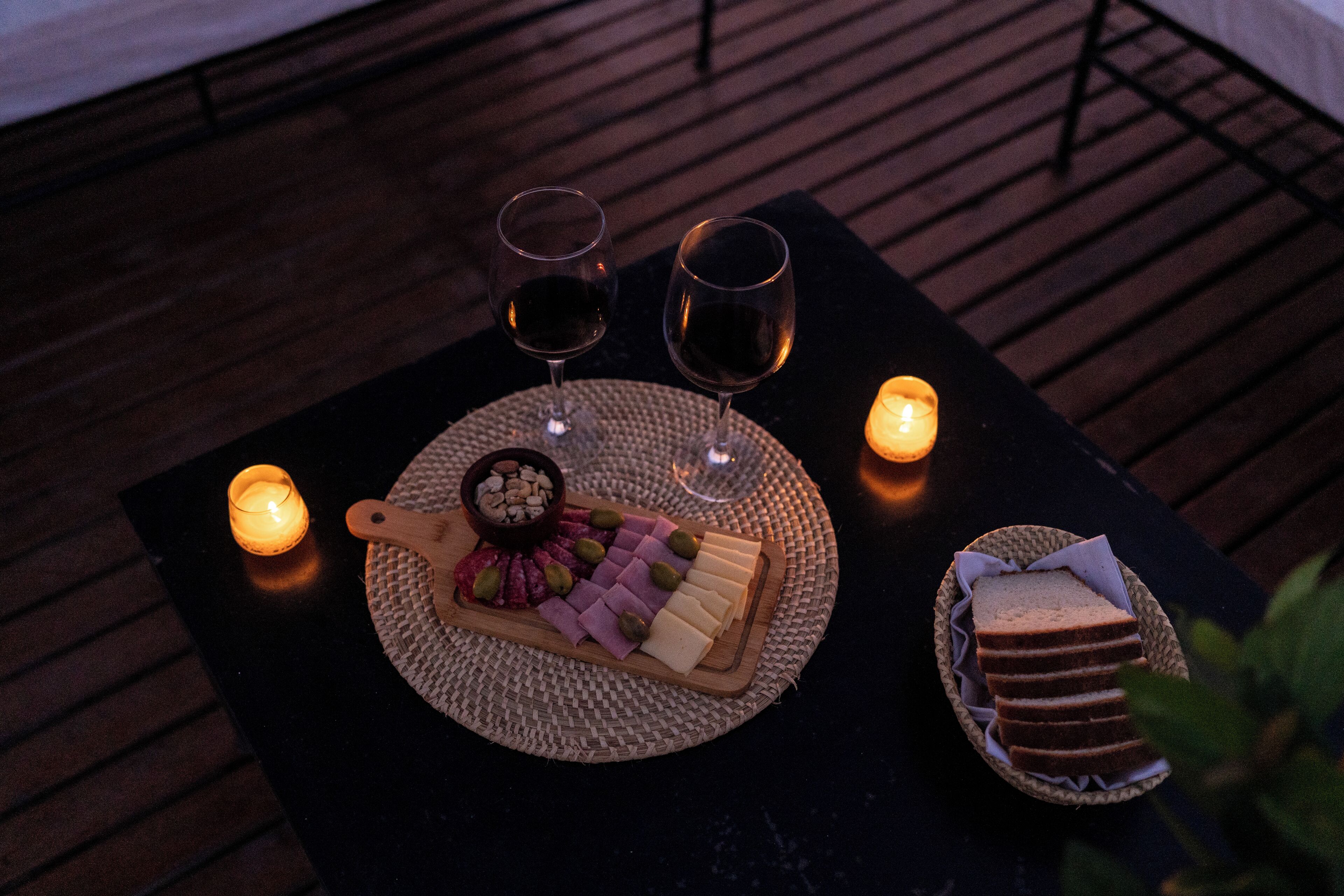 Une table avec une planche de fromages, deux verres de vin et une bougie.