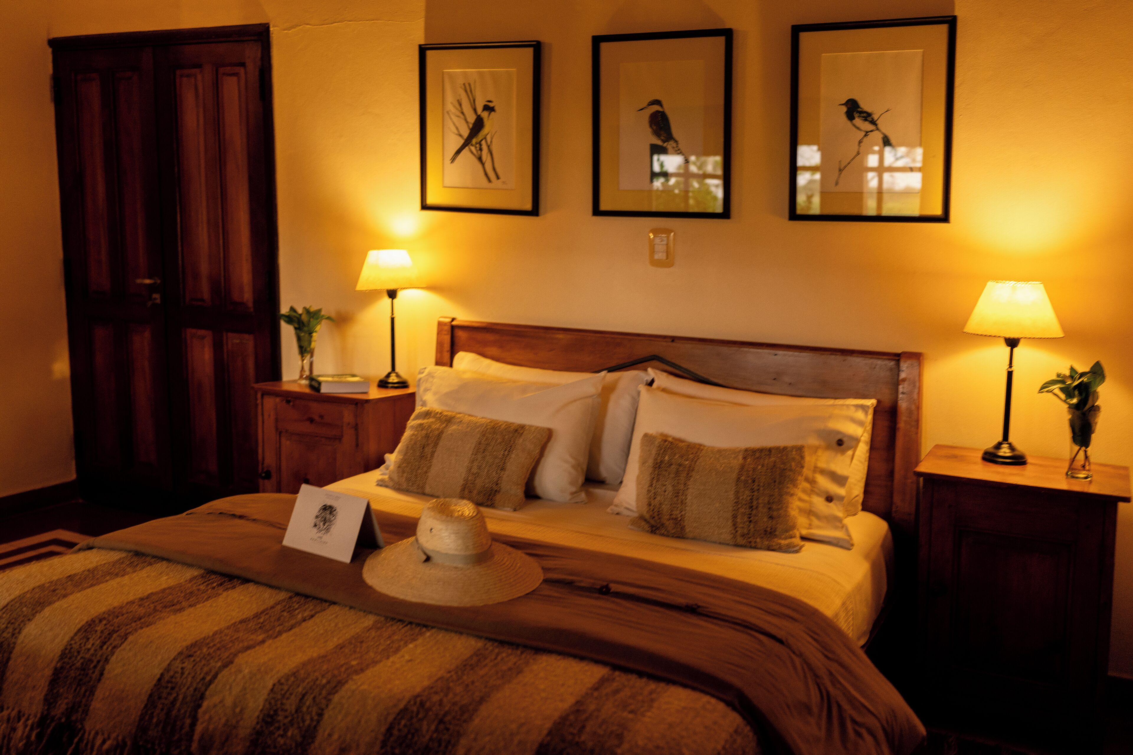 A neatly made bed with a striped blanket, two bedside lamps, and framed pictures on the wall.