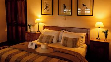 A neatly made bed with a striped blanket, two bedside lamps, and framed pictures on the wall.