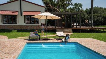 Relax by the serene pool surrounded by lush greenery and trees.