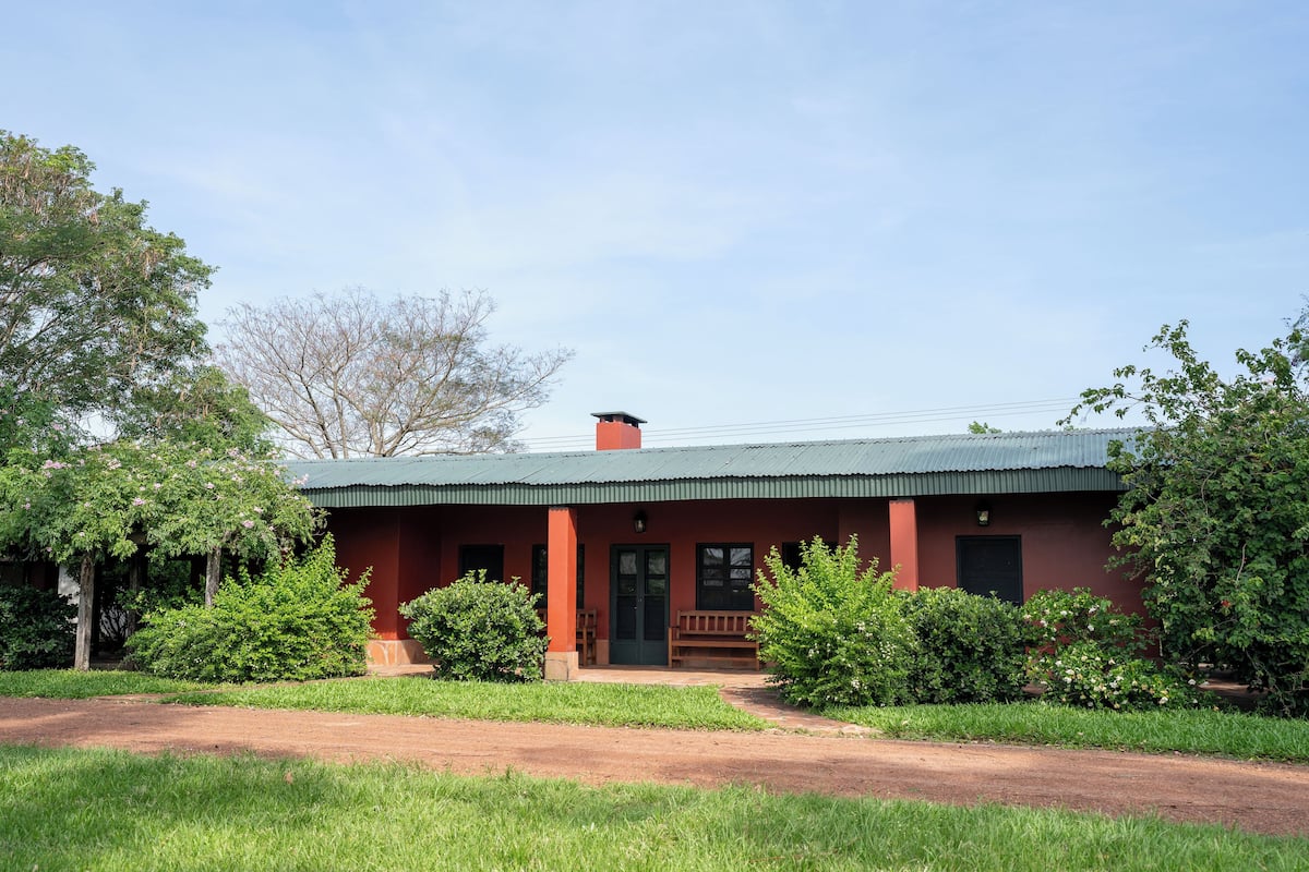 A single-story building with a green roof, a porch with benches, and a front door.