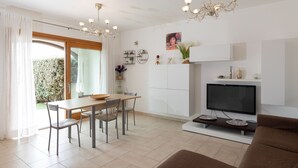 A modern living room with a flat-screen TV, a sofa, and a dining area with a table and chairs. - Casa Al Borgo by Wonderful Italy (Olbia)