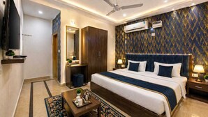 A hotel room with a bed, bedside tables, a TV, an air conditioner, and a patterned wall. -  Atlas Inn Near to IGI Airport (Firoj)