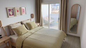 Um quarto com uma cama, mesas de cabeceira, um espelho e obras de arte na parede.