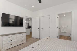 A bedroom with a bed, a TV, a dresser, and a bathroom visible through an open door. - Cliff Side Retreat 2 Bedroom Condo (Washington)