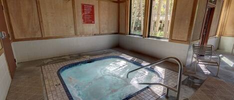 A hot tub area with tiled flooring, a metal ladder, and wooden walls.