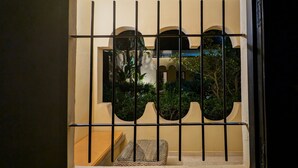 A view through a barred window with a balcony, a small wicker chair, and a glimpse of greenery outside. - Les Cypres Hotel Restaurant  (Moulay Abdallah)