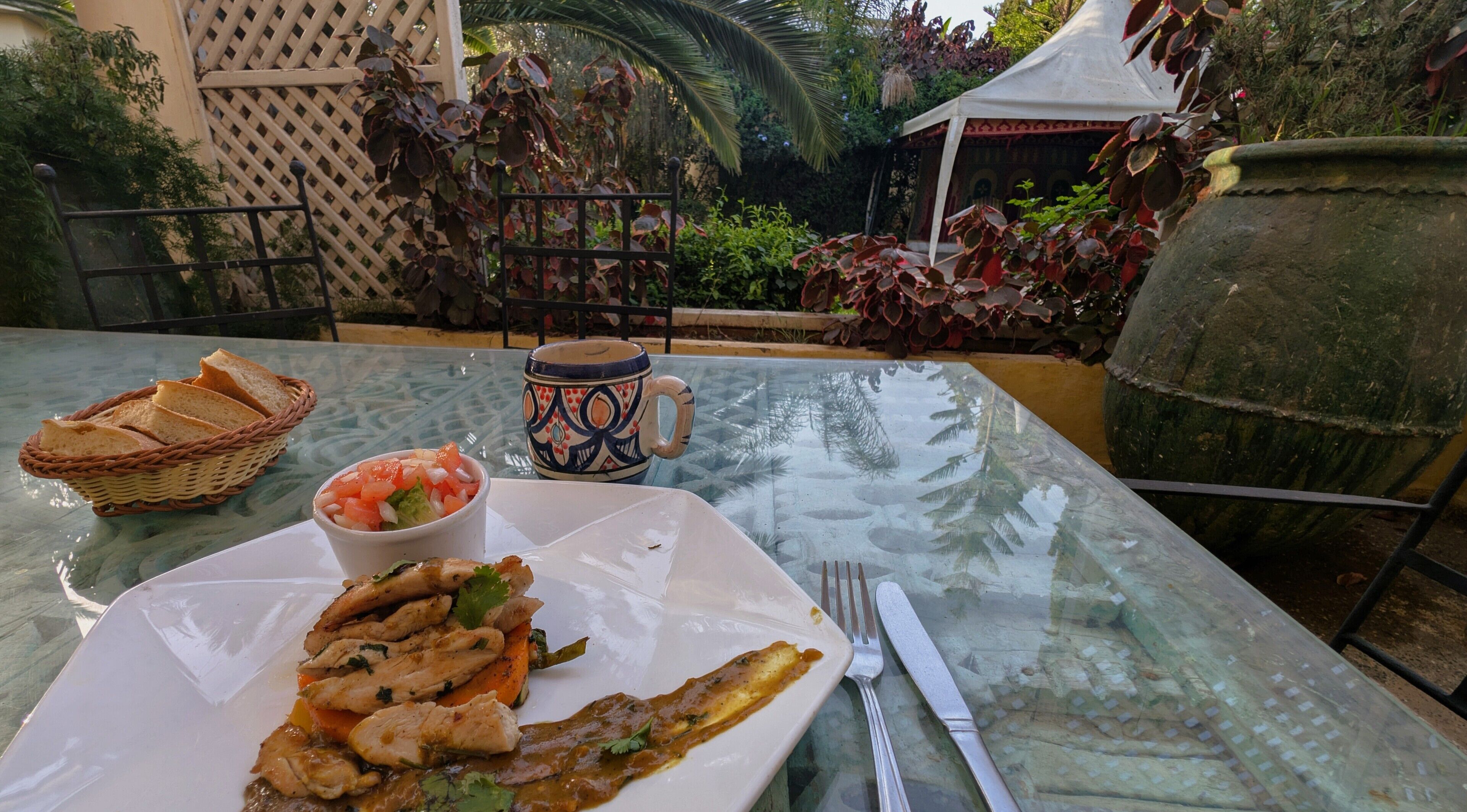 Ein Esstisch mit einem Teller Essen, einer Salatschüssel, einer Tasse und Brot.