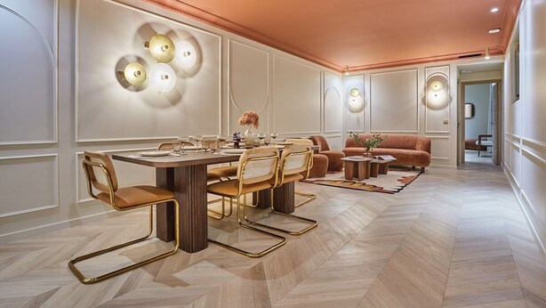 Ein moderner Essbereich mit einem Holztisch und Stühlen, einer Couch und Wandleuchten.