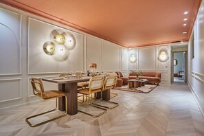 Un comedor moderno con una mesa y sillas de madera, un sofá y apliques de pared.