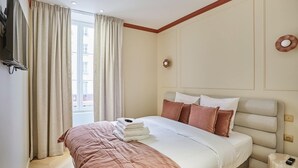 Ein Hotelzimmer mit Bett, Vorhängen, einem Fernseher und einem kleinen Tisch.