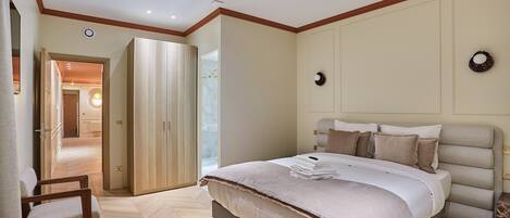 A bedroom with a large bed, a chair, and a wardrobe.