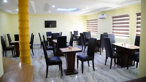 Un espace repas comprenant plusieurs tables et chaises, un grand pilier jaune et un plafond doté d’un éclairage encastré.