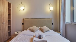 Un lit bien fait avec deux oreillers, une table de chevet avec une télécommande et une armoire avec un miroir.